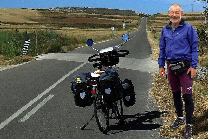 Helmut Schuller steht mit seinem Rad an einer Straße in unbewohnter Landschaft